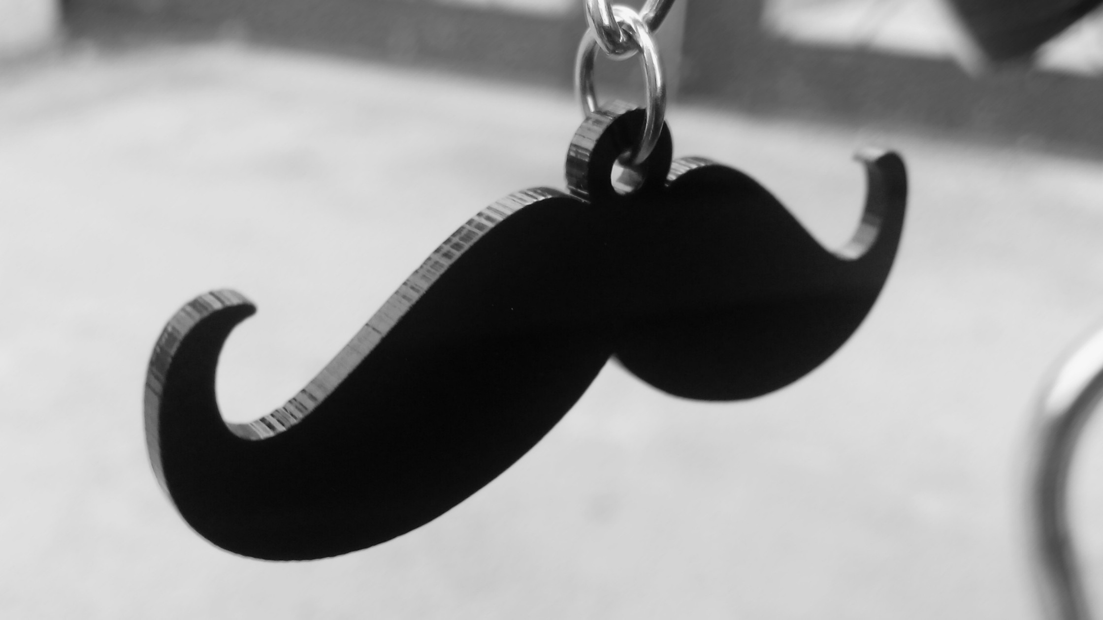 a mustache shaped black keychain up close